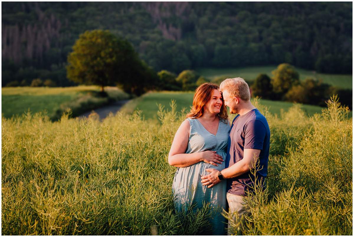 Natürliche und authentische Babybauchfotos mit Partner bei Sonnenuntergang in der freien Natur in Hattingen